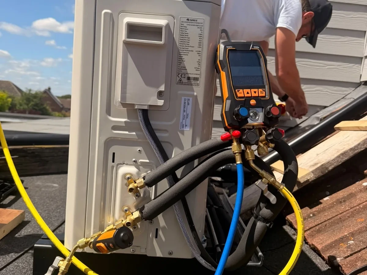 Outdoor air conditioning condenser on a brick wall with service gauges connected by Perennia Climate Services