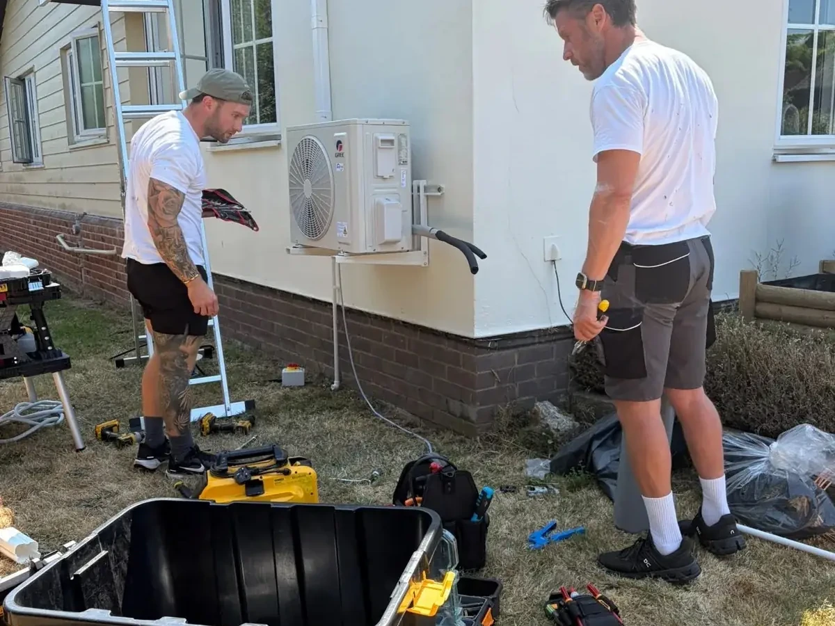 Perennia Climate Services engineer checking an outdoor air conditioning unit with manifold gauges