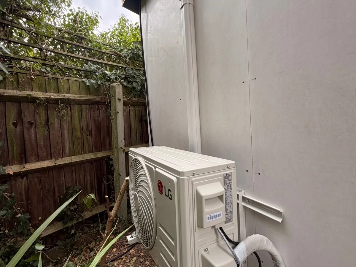 Engineer fitting a white wall-mounted air conditioning unit for Perennia Climate Services