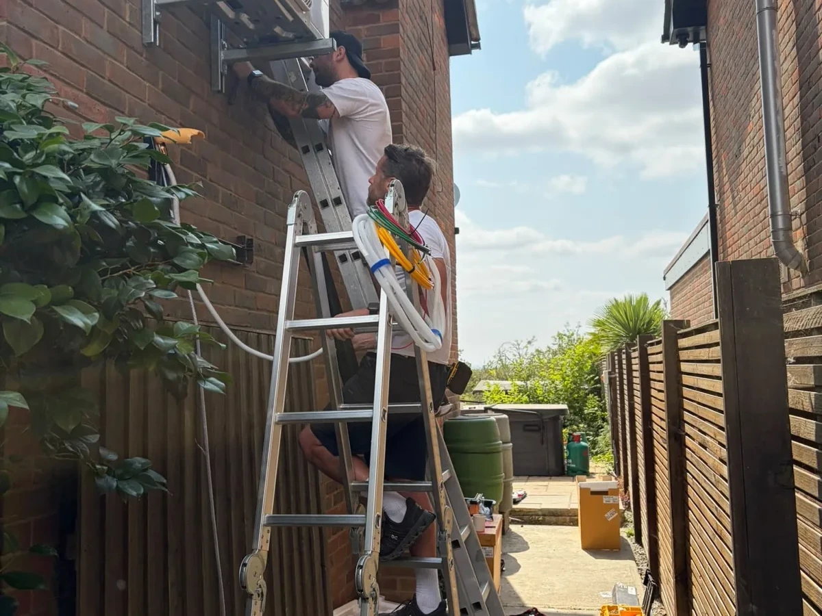 Two outdoor air conditioning units mounted on an Essex brick wall with neat pipe runs by Perennia Climate Services