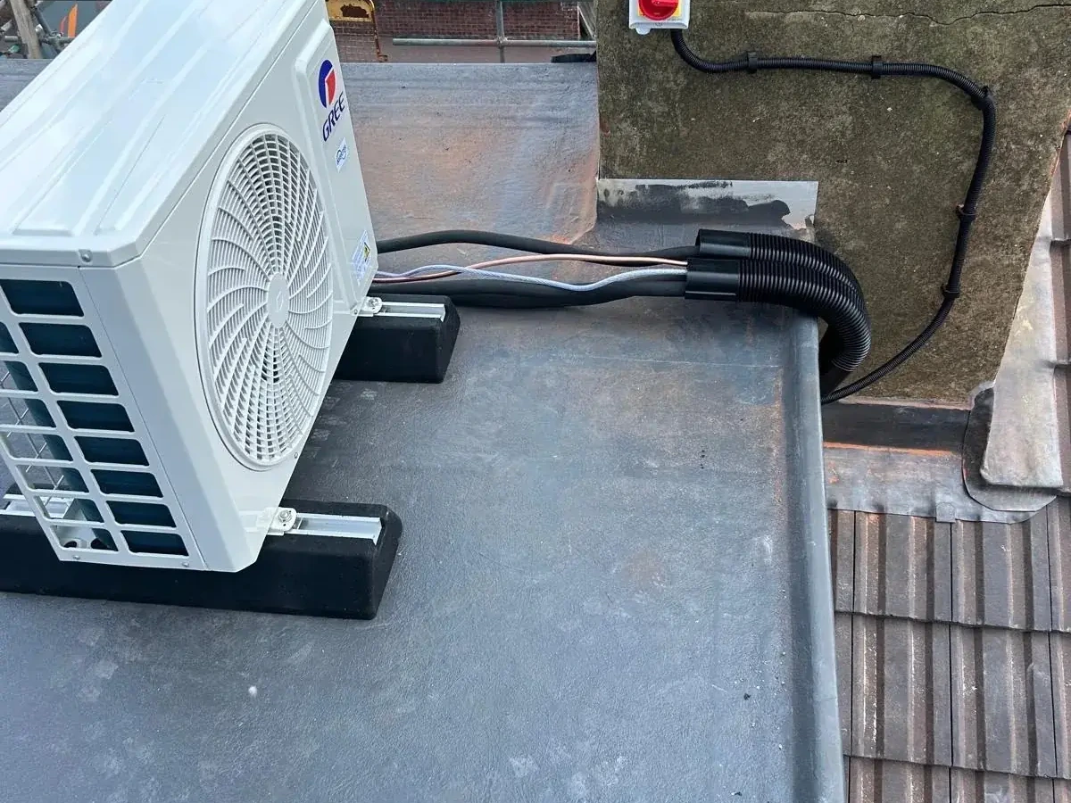 Outdoor air conditioning condenser fixed to a brick wall on a Perennia Climate Services residential job